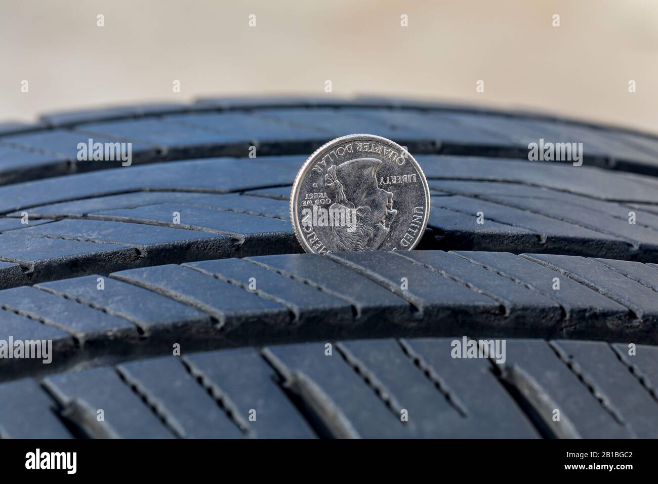 Nahaufnahme der Prüfung der Verschleißtiefe des Reifens des alten Reifens mit einer Viertelmünze. Konzept der Fahrzeugsicherheit, Wartung und Reparatur Stockfoto