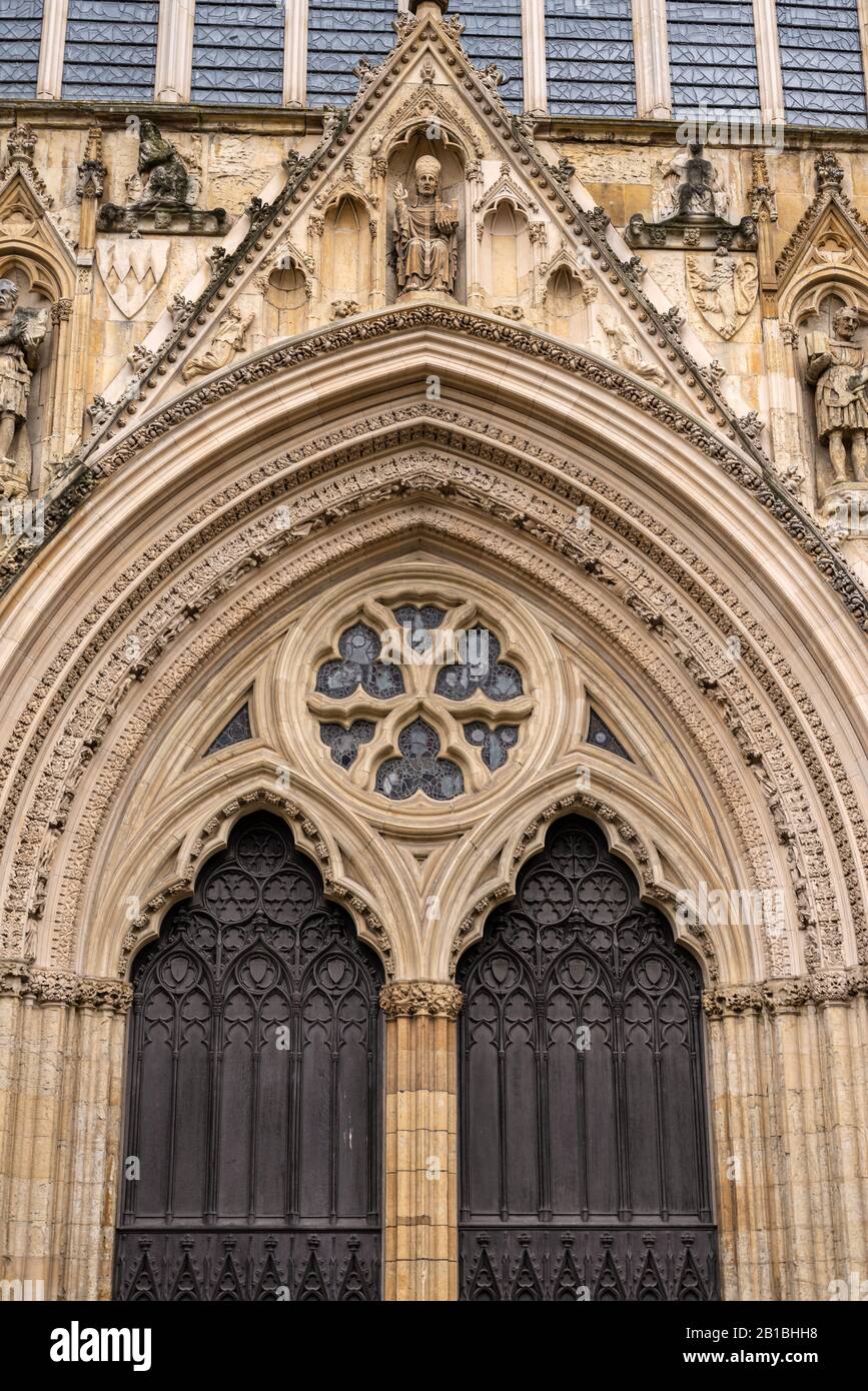 Die zentralen West-seitigen Holztüren von York Minster. In einem Archivolt sind über und auf jeder Seite des Bogens geschnitzte Figuren angebracht. Stockfoto