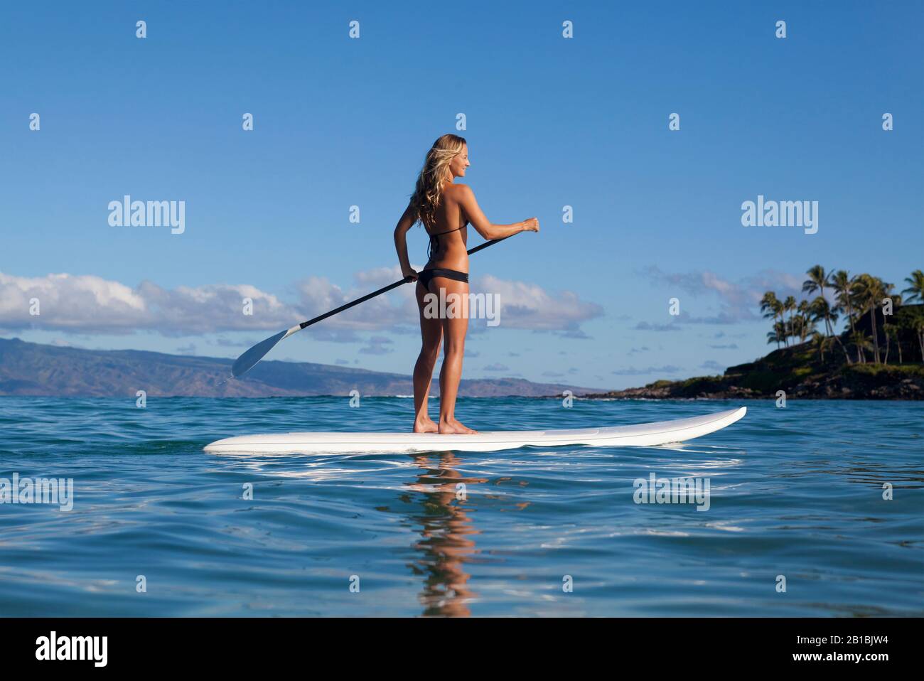 Die gesunde Frau steht in Napili Bay, Maui, Hawaii, auf den Paddles. Stockfoto