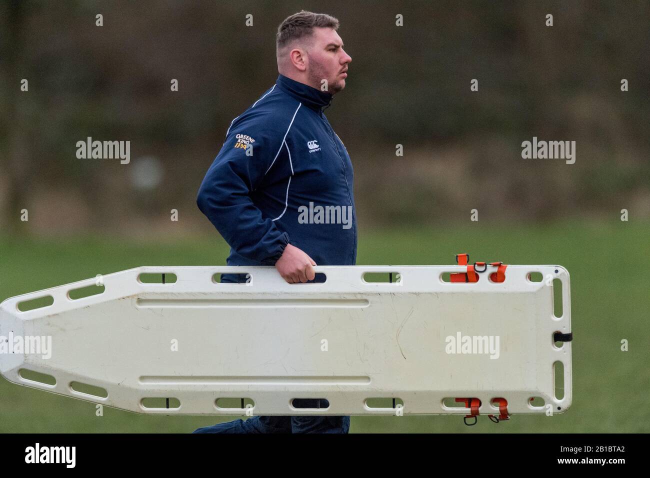 Männliches Sanitäter, das eine Bahre zu einem verletzten rugby-union-Amateur-Fußballspieler trägt. Stockfoto