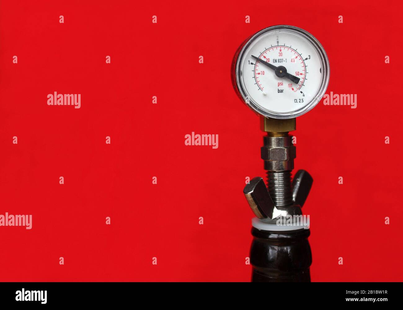 Nahansicht eines Bierflaschendruckmessers (Aphrometer) vor hellrotem Hintergrund mit Copyspace. Hausbeer-Braugeräte. Stockfoto