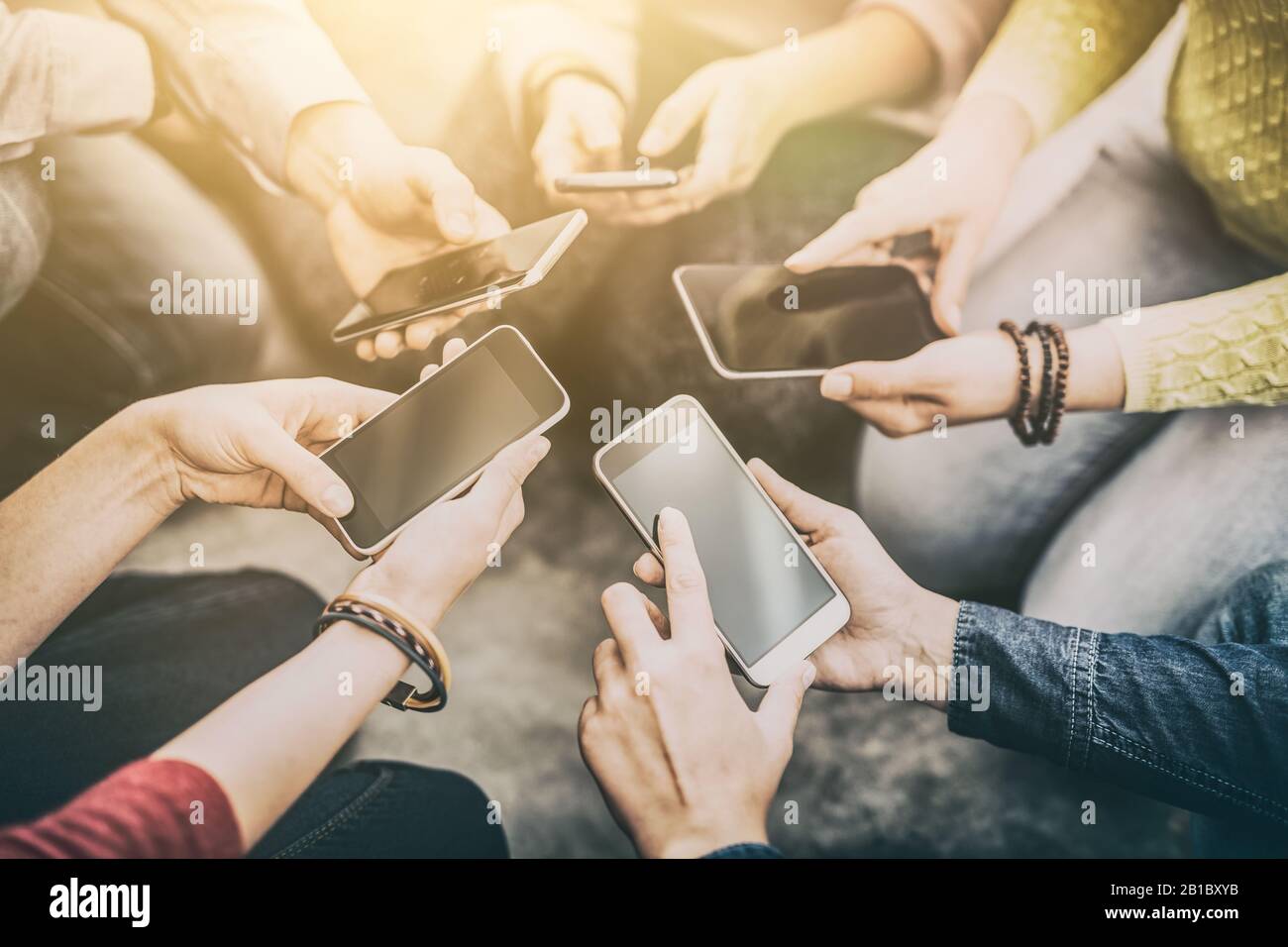 Gruppe junger Hipster, die das Telefon in den Händen halten. Freunde, die Spaß mit Smartphones haben. Stockfoto