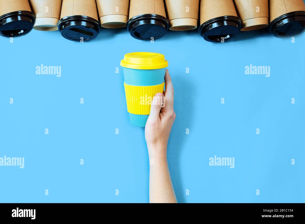 Bamboo Kaffeetassen blauer Hintergrund. Eine umweltfreundliche Kaffeetasse in weiblicher Hand. Stockfoto