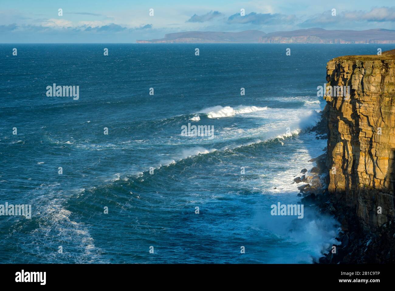 Große Wellen unter Klippen auf der westlichen Seite von Dunnet Head, Caithness, Schottland, Großbritannien. Die Insel Hoy, Orkney, in der Ferne. Stockfoto