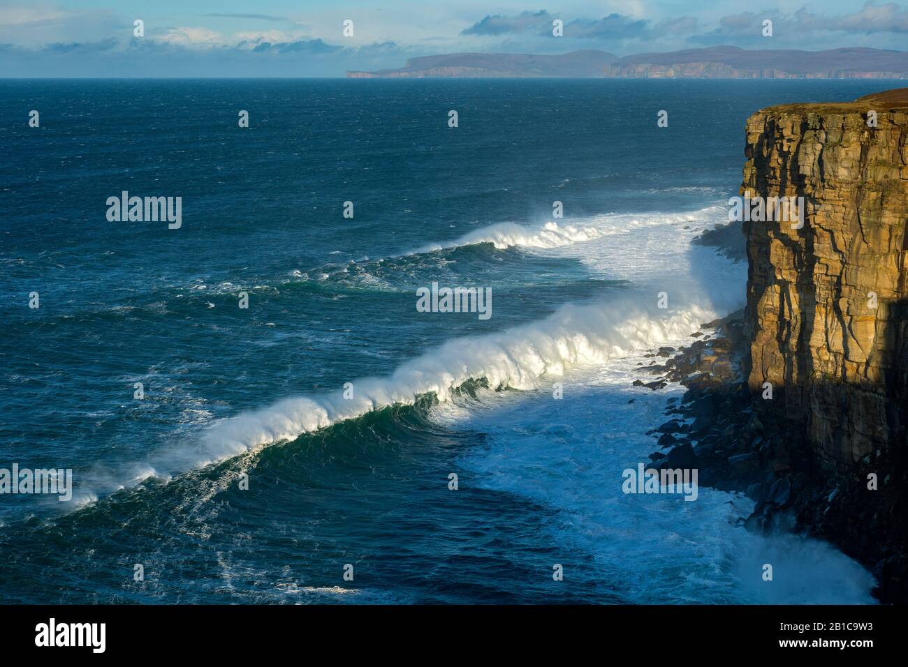 Große Wellen unter Klippen auf der westlichen Seite von Dunnet Head, Caithness, Schottland, Großbritannien. Die Insel Hoy, Orkney, in der Ferne. Stockfoto