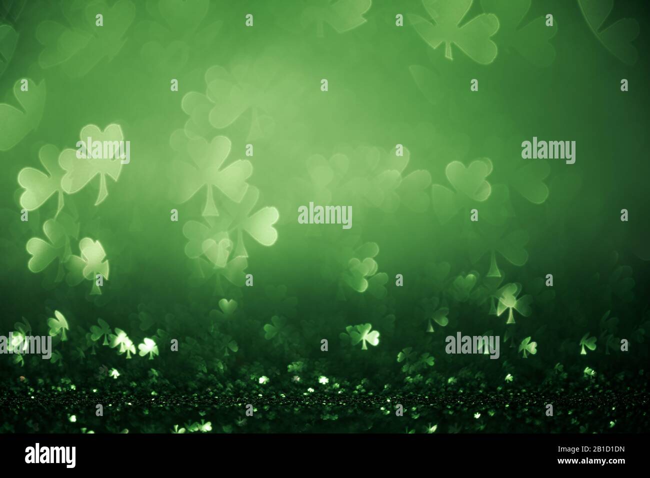 Grüner St. Patricks Tageshintergrund mit funkelnden Shamrockformen Stockfoto