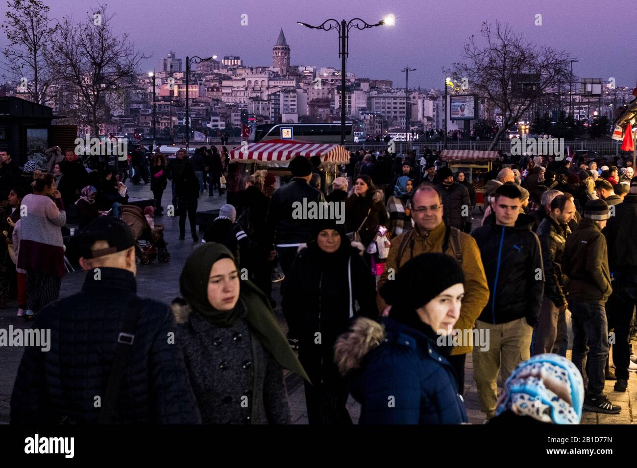 Menschen, die nach Sonnenuntergang in Eminönü, einem Viertel von Istanbul, mit dem Galata-Turm im Hintergrund spazieren gehen Stockfoto