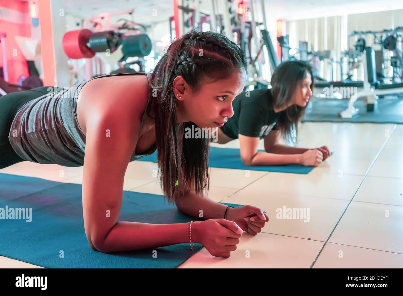 Fit Mädchen in der Sporthalle das Planktraining für Rückenwirbel und das Körperhaltung Konzept führt zum Sport Stockfoto