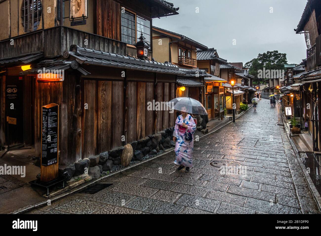 Kyoto, Japan, 15. August 2019 - Frau, die einen traditionellen Yukata (Kimono) trägt, der unter dem Regen mit einem Regenschirm im historischen Bezirk von Kyoto in der Higa spazieren geht Stockfoto
