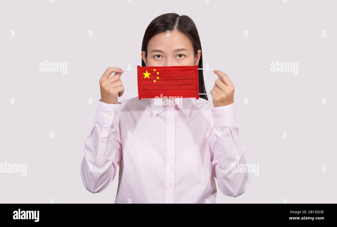 Asiatische Frau, die hygienische Maske trägt, die chinesische Flagge zum Schutz vor dem Coronavirus 2019 (COVID-19) Infektionsausbruch, dem Virusursprung, gemalt hat Stockfoto