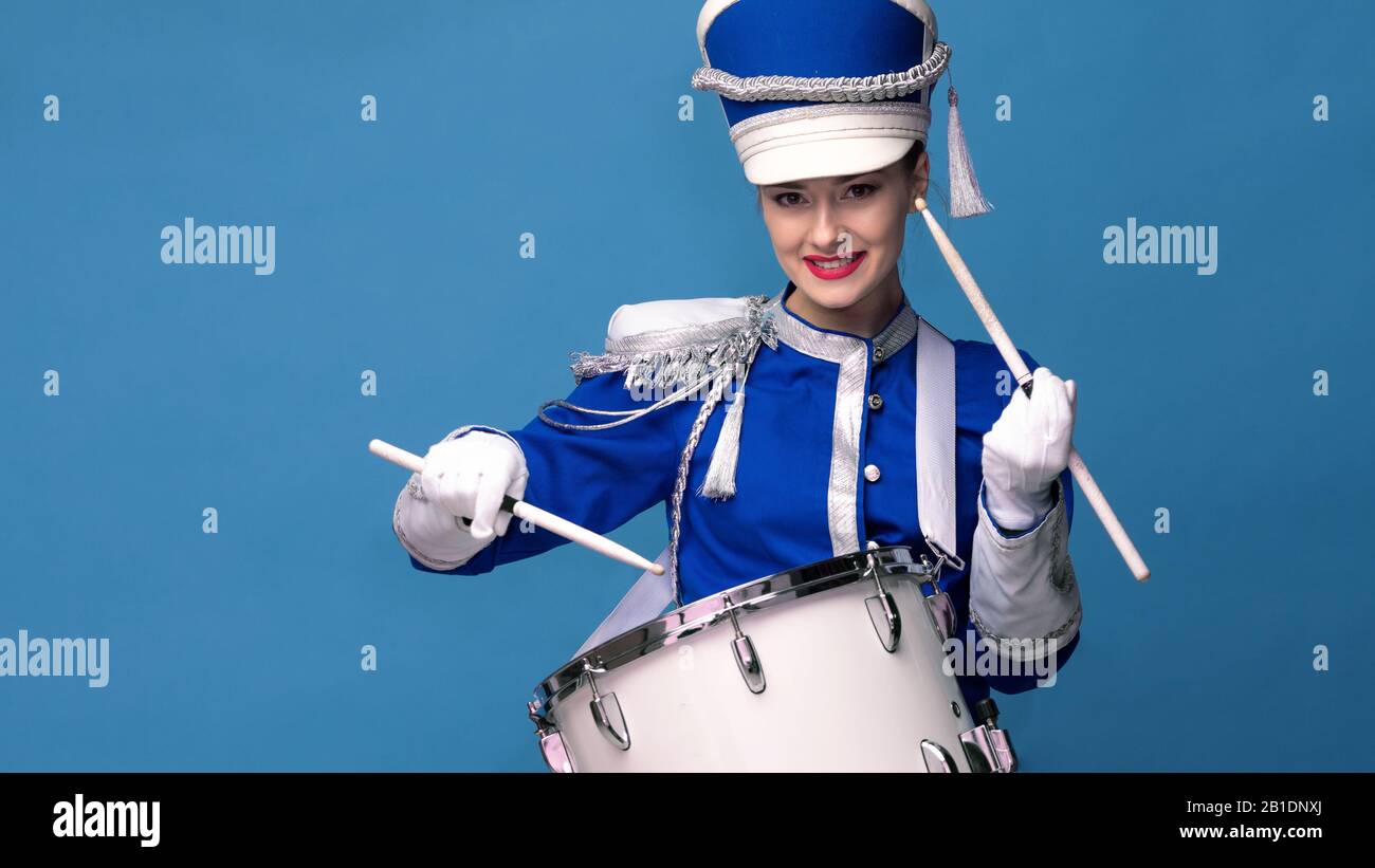 Charmanter fröhlicher Schlagzeuger in blauer Uniform, singt und spielt die Trommel. Blauer Hintergrund, Kopierbereich Stockfoto