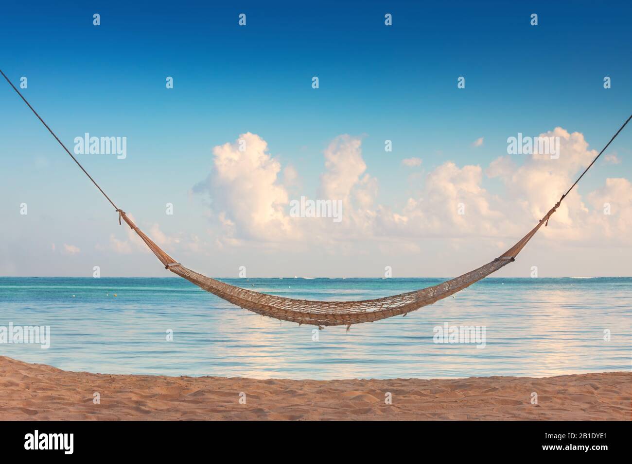 Leere Hängematte unter hohen Palmen am tropischen Strand. Stockfoto