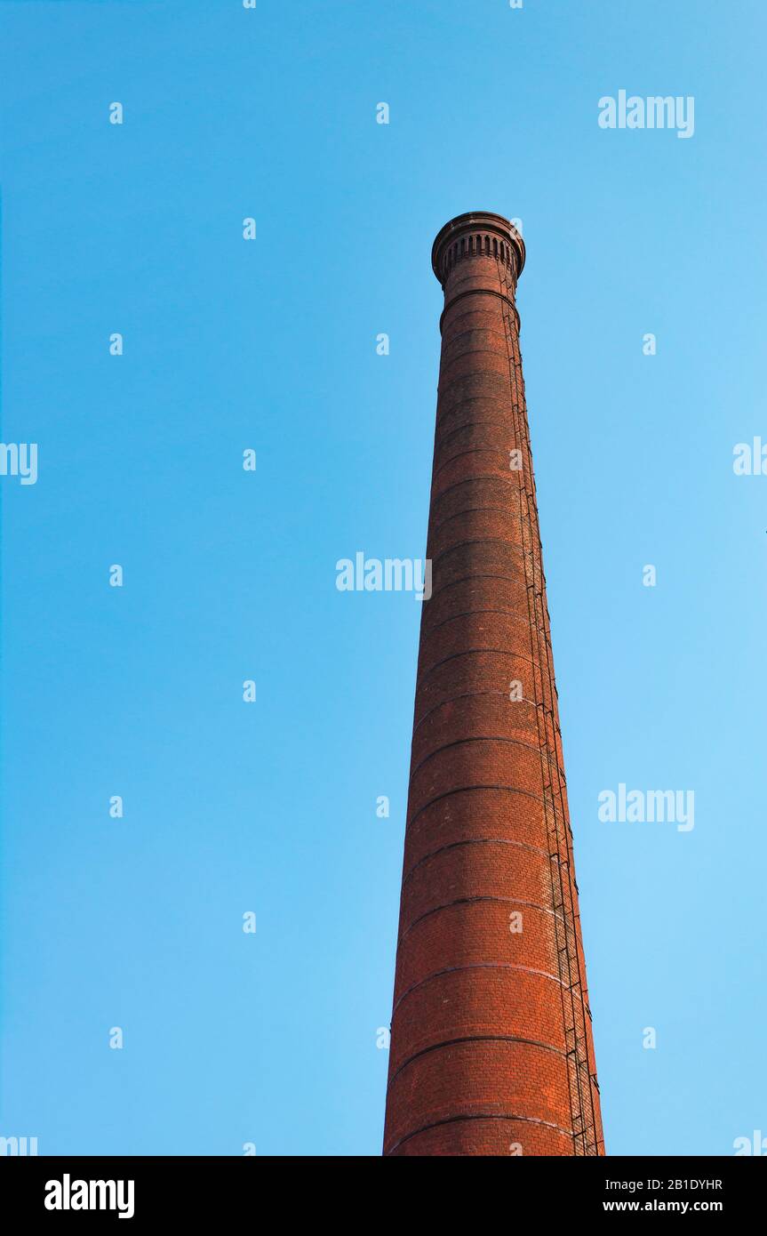Werkrohr aus rotem Backstein gegen blauen Himmel. Das Konzept der Umweltverschmutzung durch schädliche Emissionen in die Atmosphäre. Stockfoto