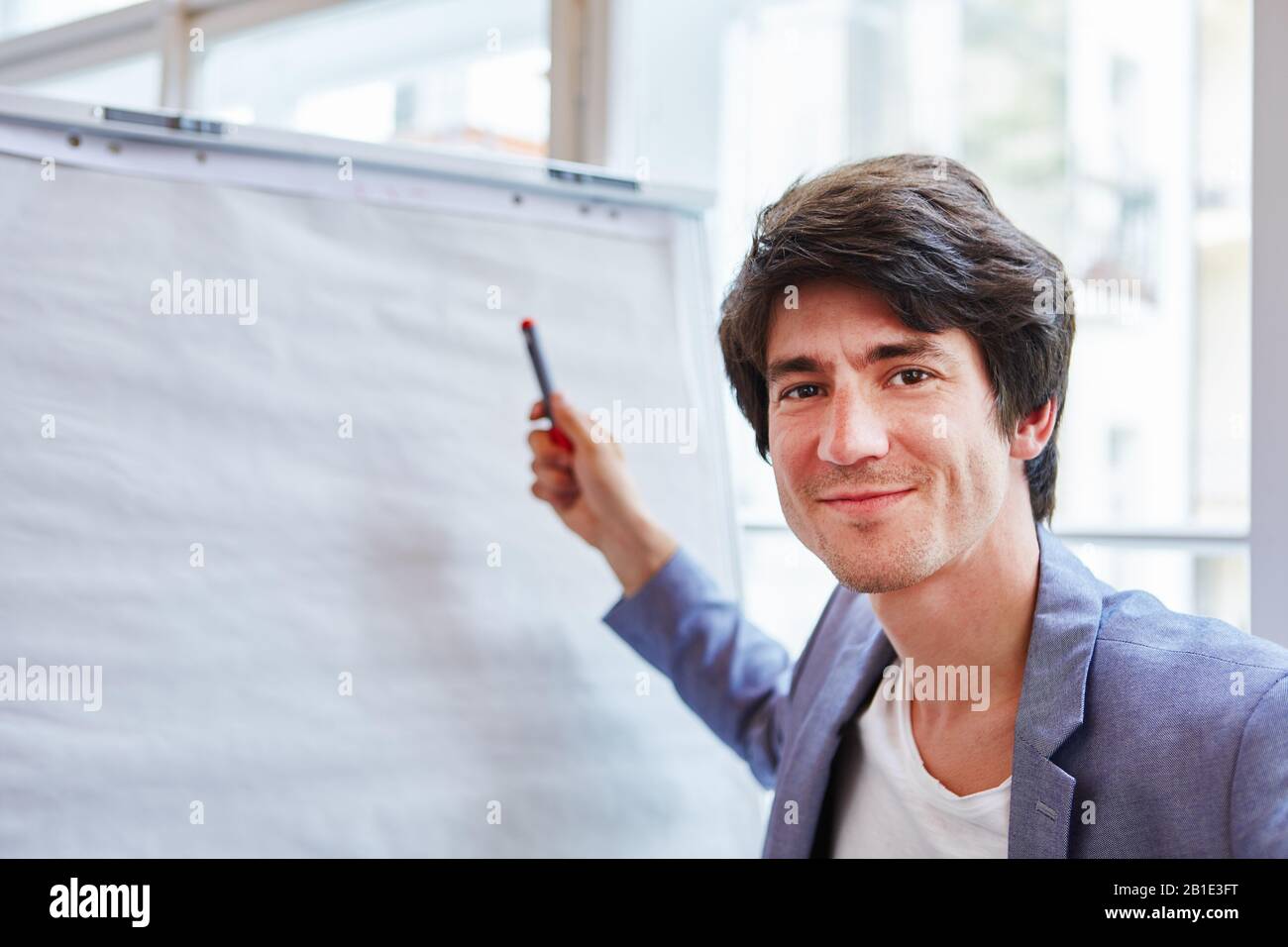 Junger Geschäftsmann von Start-up steht mit Stift vor einem Flipchart Stockfoto