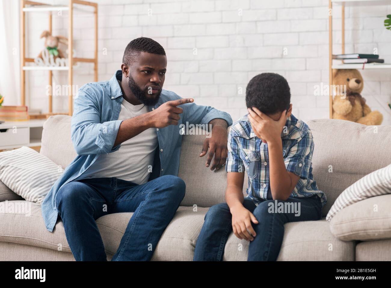 Wütender schwarzer Vater schimpft hartnäckigen Sohn wegen schlechten Verhaltens zu Hause Stockfoto