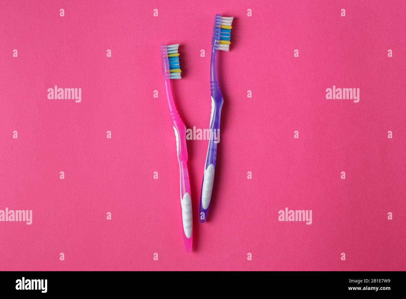 Die alten pinkfarbenen und violetten Zahnbürsten sind auf dem rosafarbenen Hintergrund abgelaufen (beschädigt). Kunststoff-Verschmutzungskonzept Stockfoto
