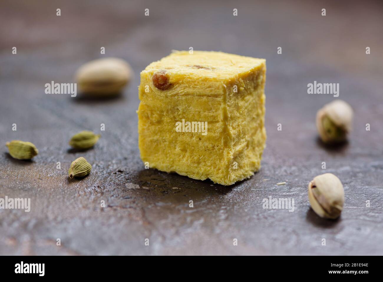 Ein Würfel aus Dessert soan Papdi, Kardamom-Körnern und Pistazien auf Betonküchenoberfläche. Stockfoto