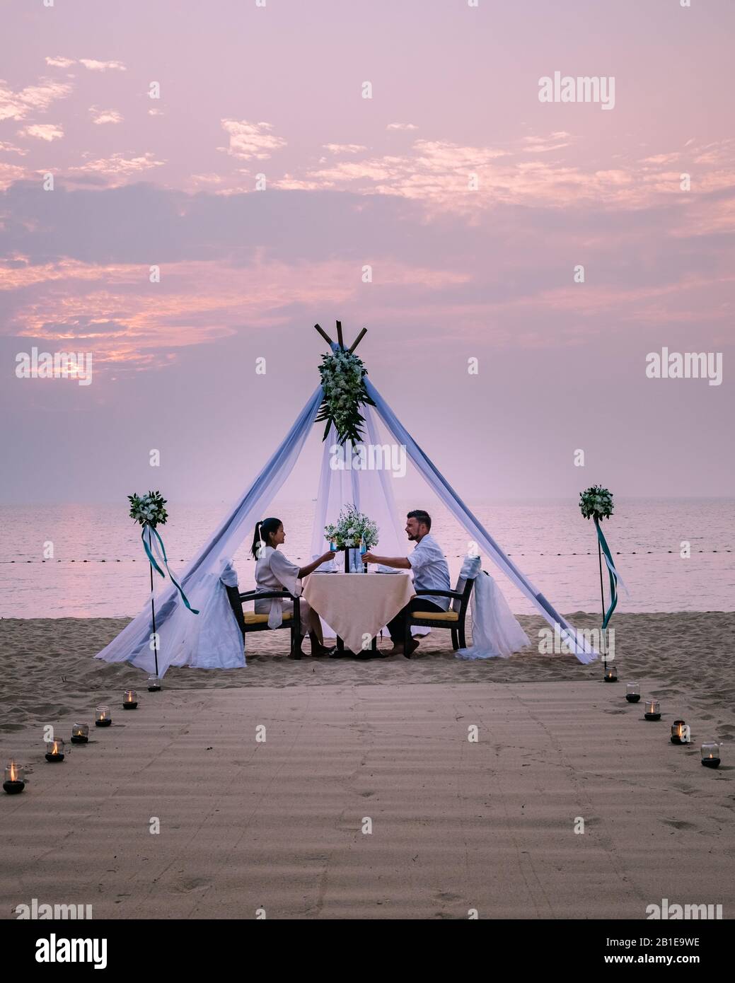 Junge Paare Flitterwochen-Abendessen bei Kerzenlicht bei Sonnenuntergang am Strand, Männer und Frauen Abendessen am Strand romantische Einstellung in Thailand Stockfoto