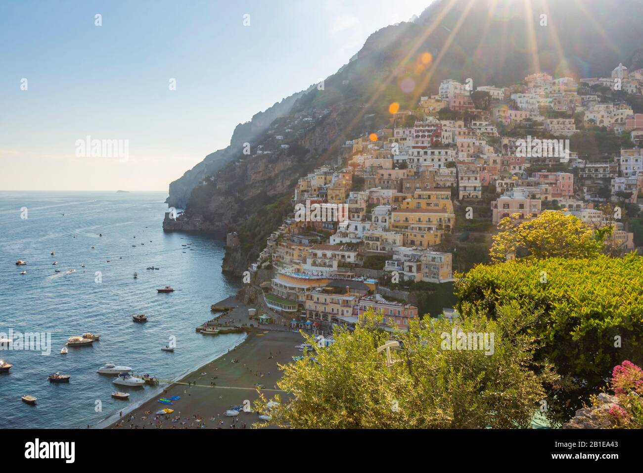 Fantastischer Blick auf die Positano-Stadt und das Meer bei einem Sommeruntergang. Sonnenstrahlen mit Linsenflare. Stockfoto