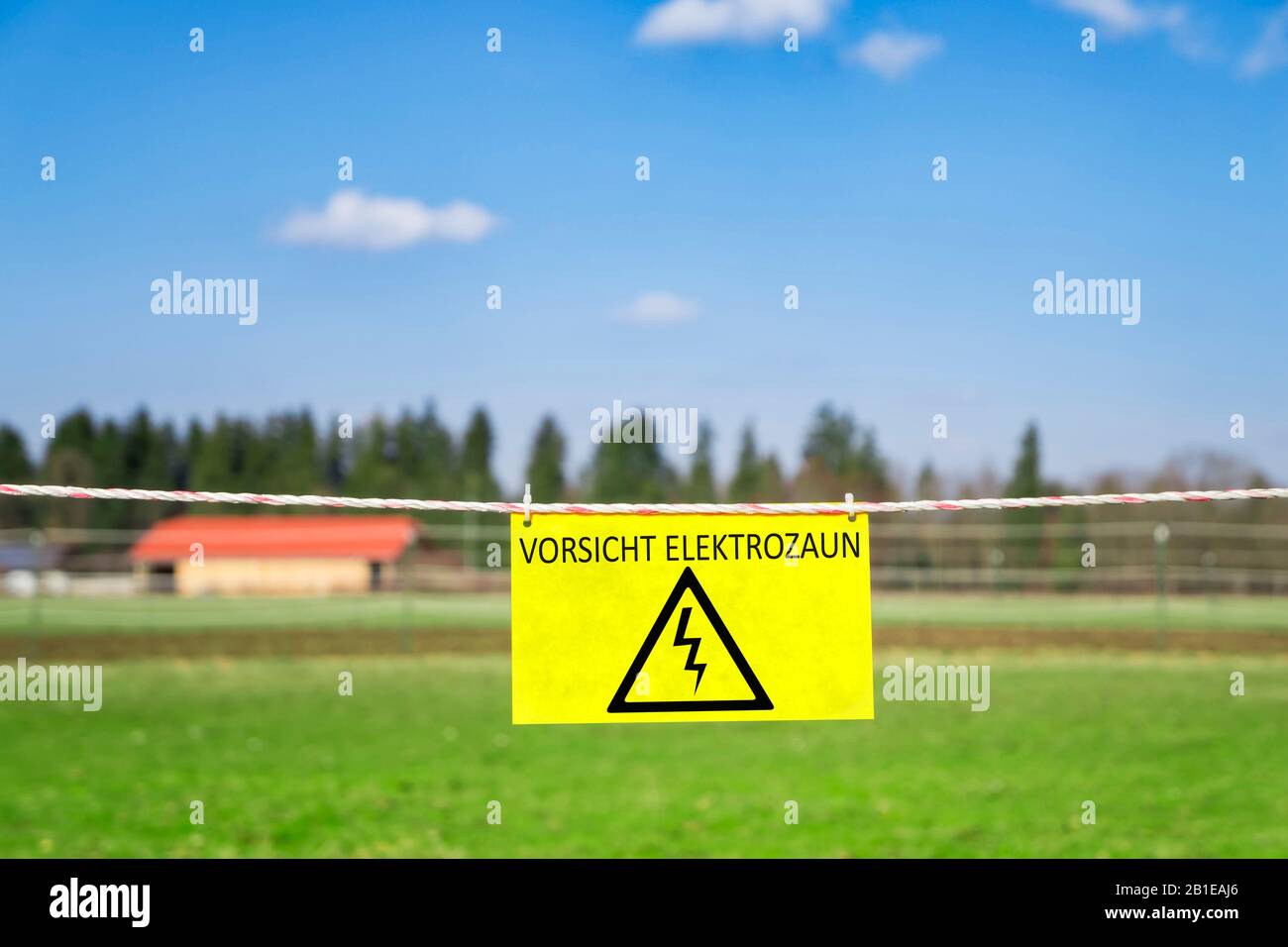 Elektrifizierter Zaun mit gelbem Warnschild VORLICHT ELEKTOZAUN (Elektrischer Gefahrenzaun) Stockfoto