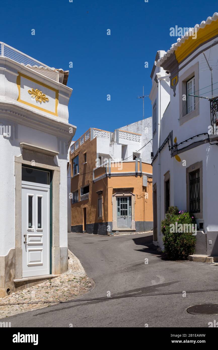 Enge Straße einer Altstadt an einem sonnigen Tag mit blauem Himmel. Häuser mit meist weißer Fassade. Estoi, Portugal. Stockfoto