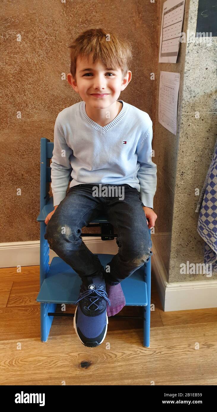 Kleiner Junge auf einem Holzstuhl sitzend, grinsend, Deutschland Stockfoto