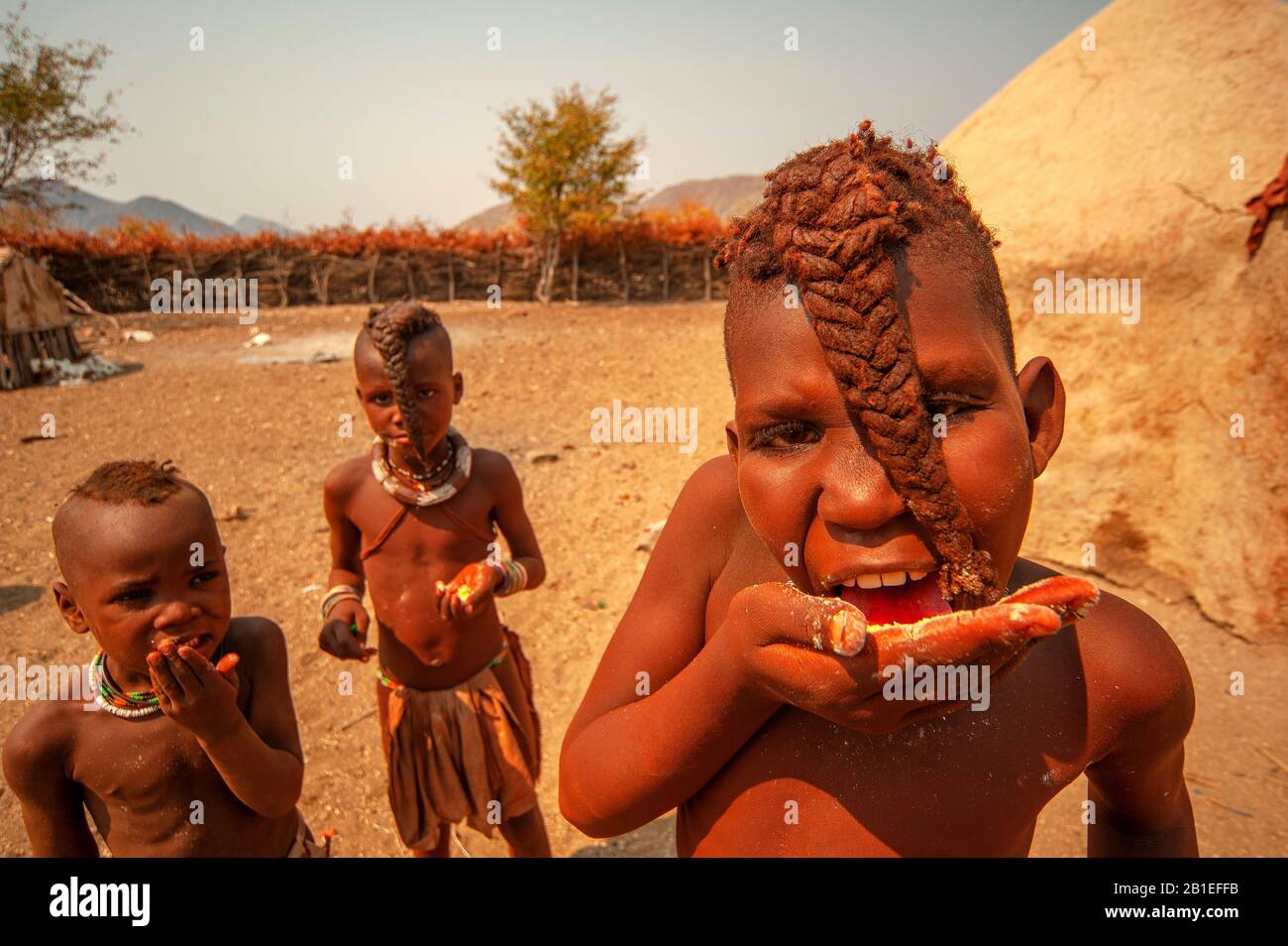 Himba-Jungen essen Rohkornmehl in ihrem Dorf in der Nähe der Epupa-Fälle, in Namibia Stockfoto