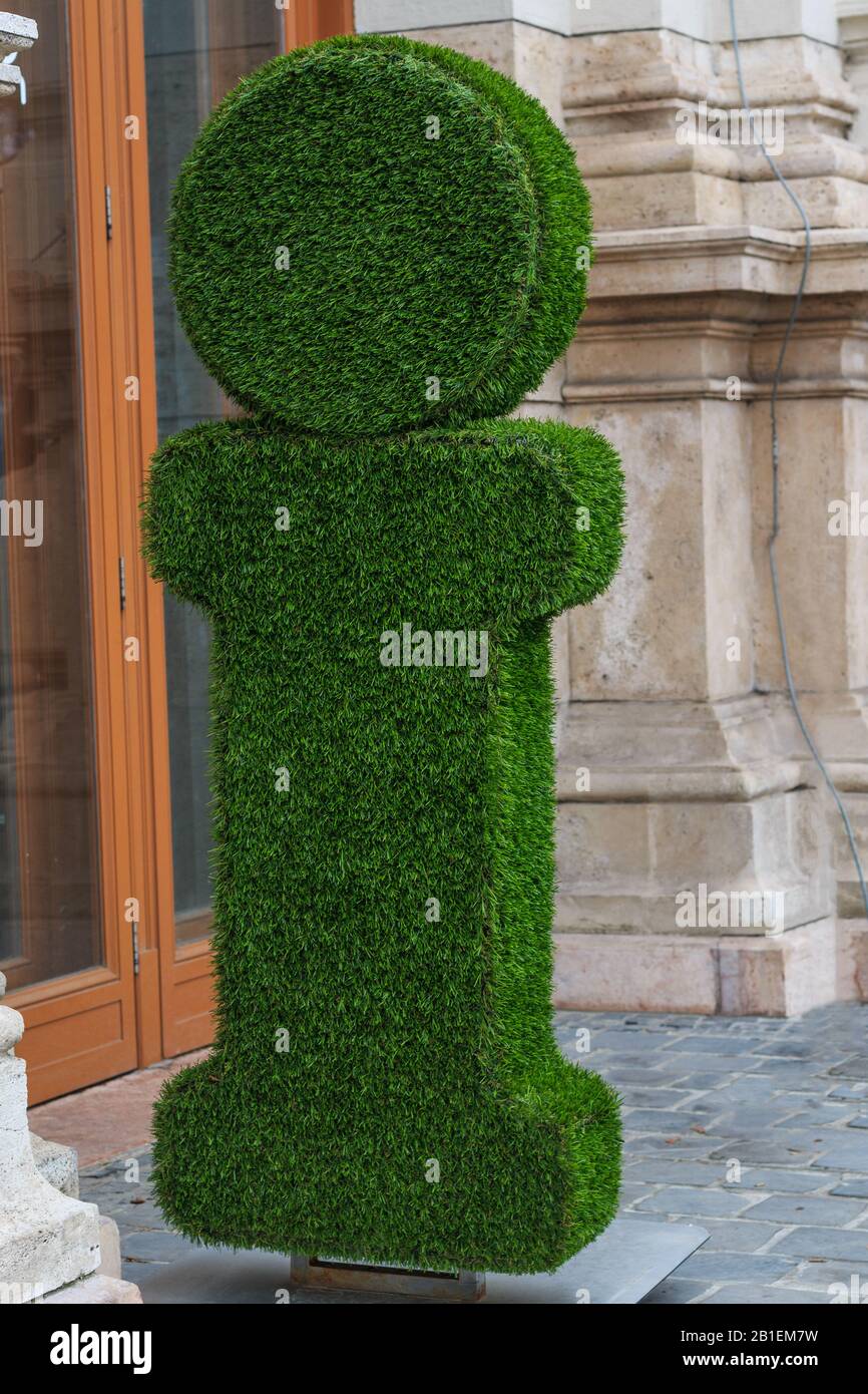 Ein großer grüner i-Brief, ein Schild mit einem Informationsstand, das mit grünem Gras bedeckt ist, das draußen an einem Eingang einer Glastür steht Stockfoto