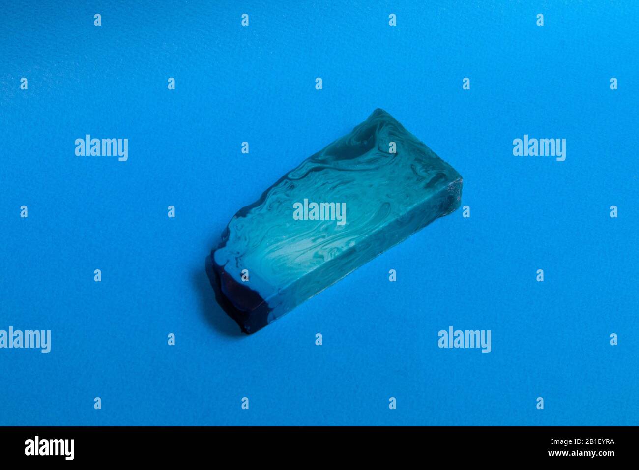 Dünnes, flaches Stück blaue Minze handgemachte Seife vor hellblauem Hintergrund im Pop-Art-Stil Stockfoto