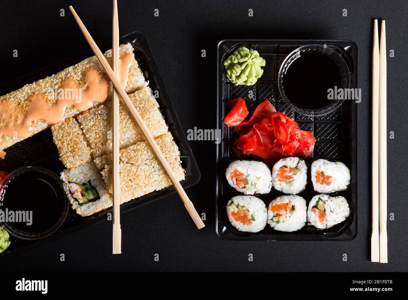 Verschiedene Sushi-Typen in Boxen. Sushi-Sets auf schwarzem Hintergrund. Stockfoto