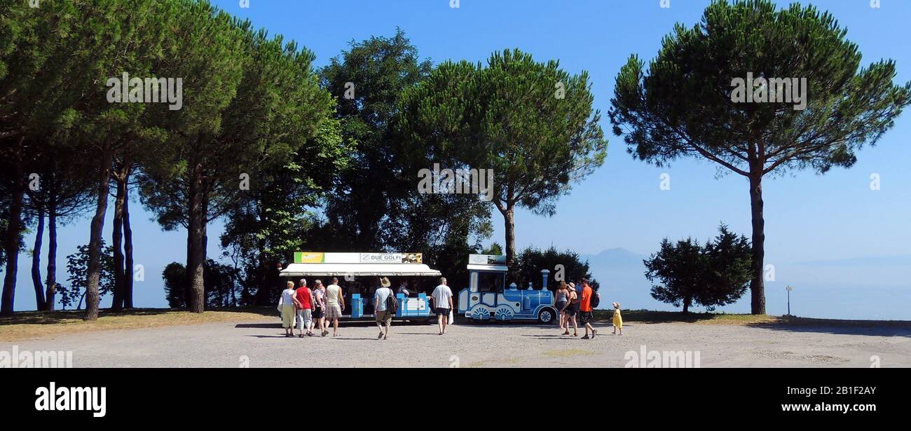 Italienischer TOURISTENZUG (STRASSE) (Du Golfi) mit einem nebligen Vesuv im Hintergrund (rechts) in Sant Agata, Provinz Neapel. Der Zug, der auf dem Parkplatz des Klosters der Wüste des Hügels (Monastero di San Paolo) geparkt war, wo die Karmeliter-Brüder zunächst ein Refugium errichteten, das heute den Ordensfrauen des heiligen Paul gehört. Stockfoto