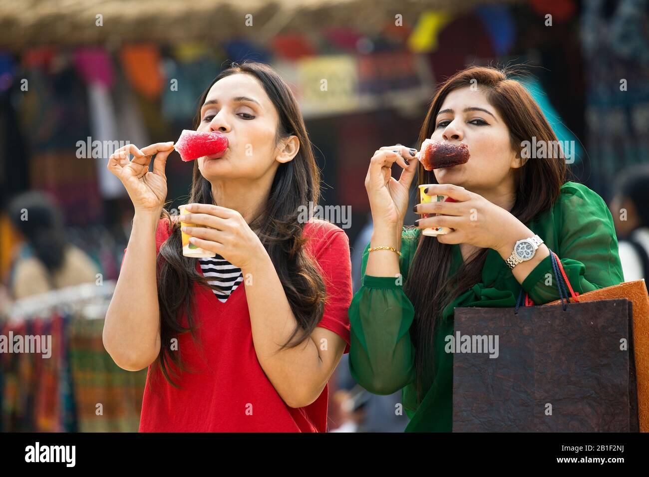 Zwei Frauen, die aromatisiertes Eis verzehren, tauchte gola in Sirup Stockfoto