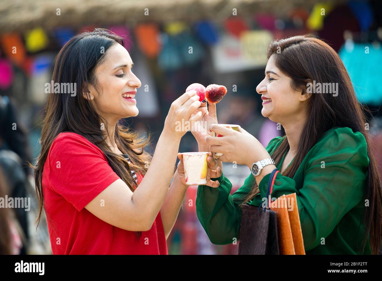 Zwei Frauen, die aromatisiertes Eis verzehren, tauchte gola in Sirup Stockfoto