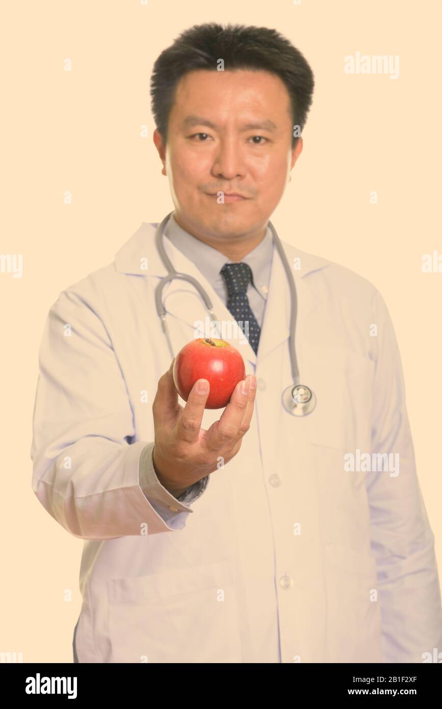 Studio shot der japanischen Mann Arzt holding red apple mit Schwerpunkt auf Apple Stockfoto