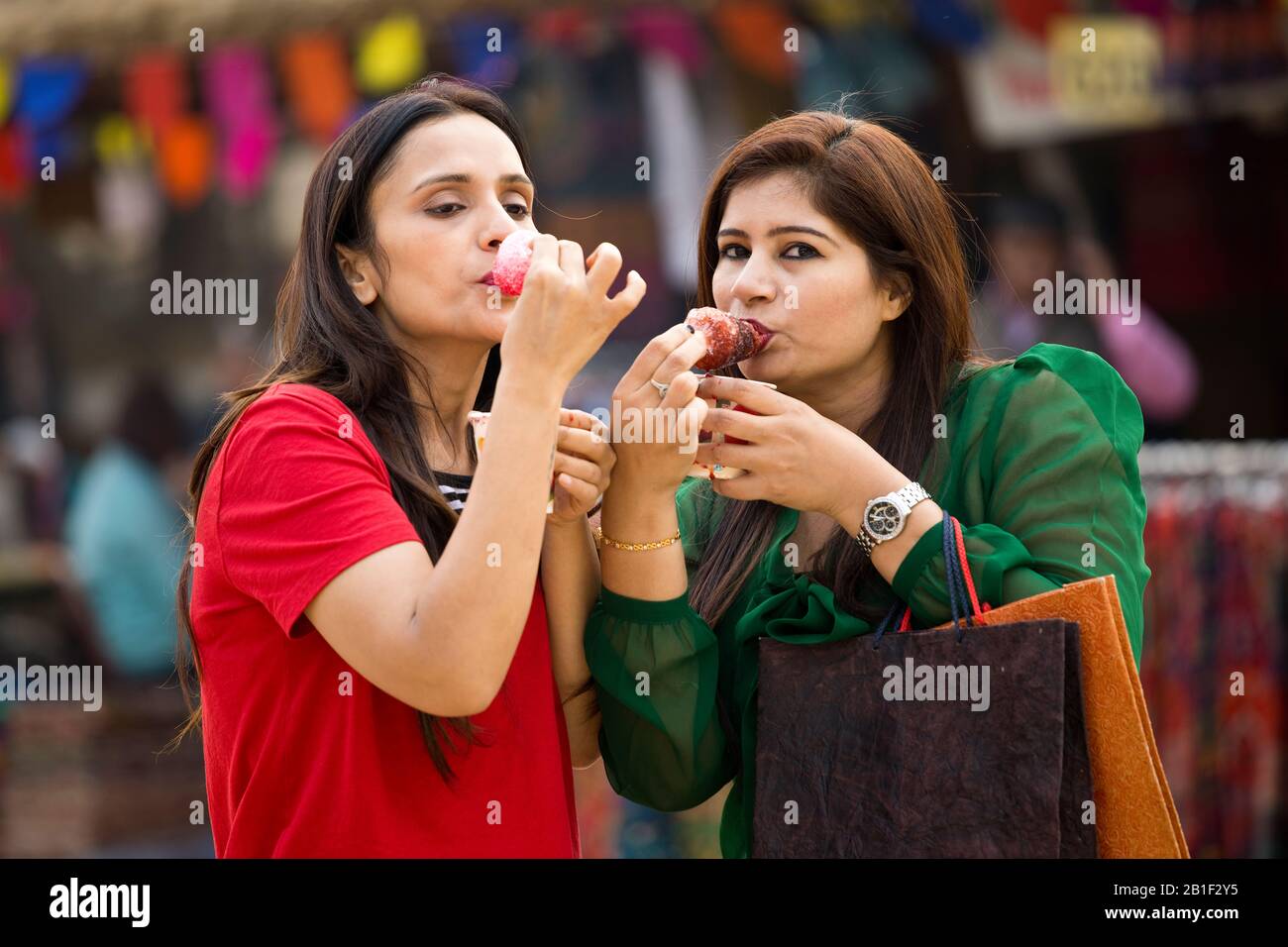 Zwei Frauen, die aromatisiertes Eis verzehren, tauchte gola in Sirup Stockfoto