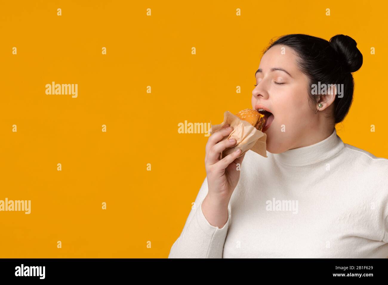 Hungry Plus Size Girl, Das Burger Mit Geschlossenen Augen Isst Stockfoto