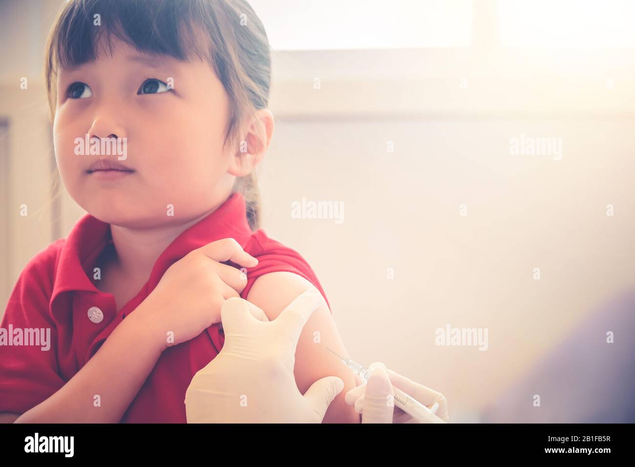 Asiatisches Kleinkind mit Injektion, Nahaufnahme Des Arztes, der Impfung gegen Arm der Impfstoffinjektion kleiner Mädchen im Krankenhaus zur Immunisierung befürchtet Stockfoto