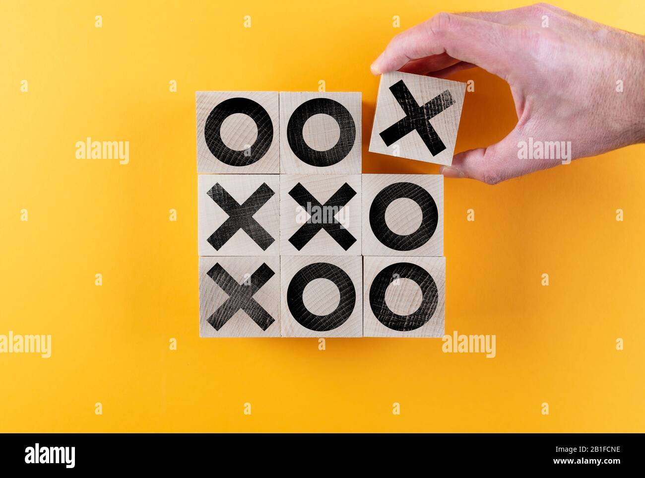 Draufsicht über Tic-tac-Toe-Spiel auf Holzspielzeugblöcken vor orangefarbenem Hintergrund, Sieg- und Scoring-Konzept Stockfoto