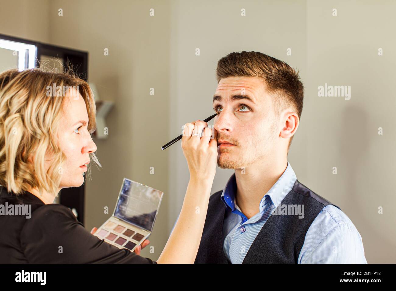 Hinteres Foto der Visagiste bei der Arbeit, die Modell-Makeup macht. Stockfoto