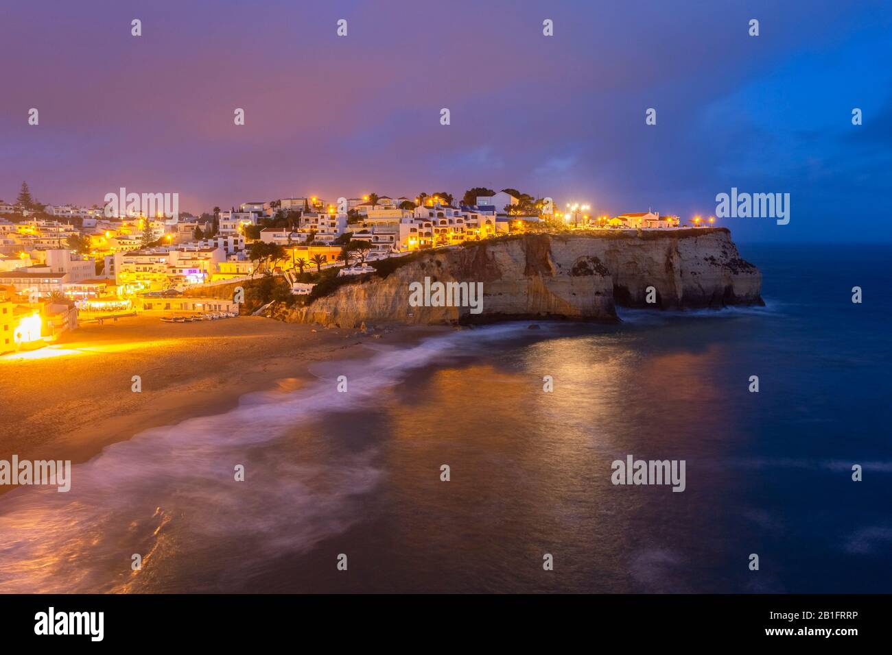 Blick auf die Lichter des Dorfes Carvoeiro und seinen Strand bei blauer Stunde. Lagoa Gemeinde, Algarve, Portugal, Europa. Stockfoto