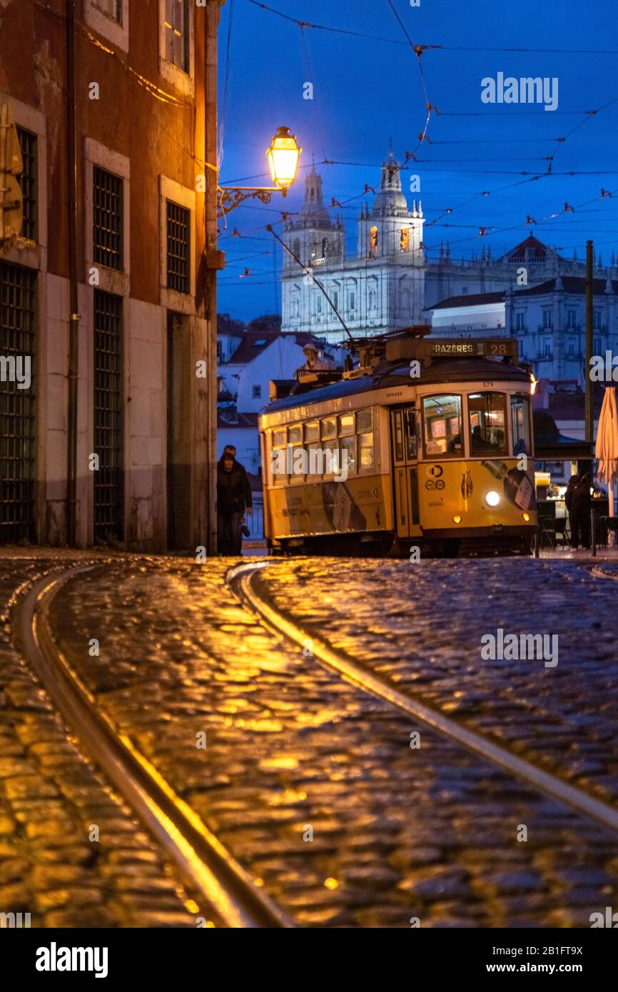 Die Straßenbahn Nr. 28 führt am Abend mit dem Kloster São Vicente de Fora auf die Straßen des Stadtteils Alfama. Lissabon, Portugal, Europa. Stockfoto