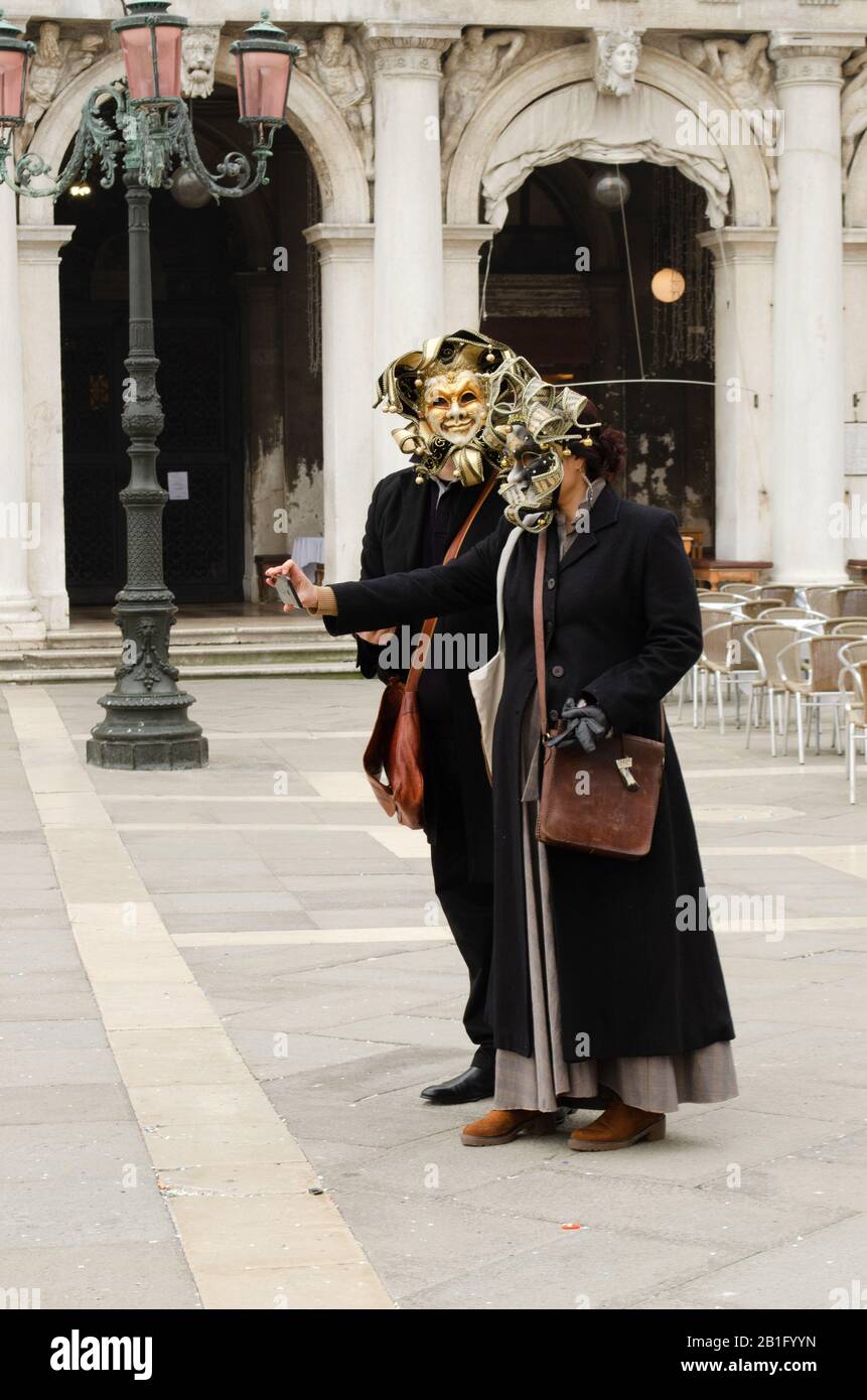 Menschen, die sich noch immer in der karnevalskostüm von venedig auf dem Markusplatz befinden, trotz der Bedrohung durch Coronavirus und der Festlichkeiten, die abgesagt wurden Stockfoto