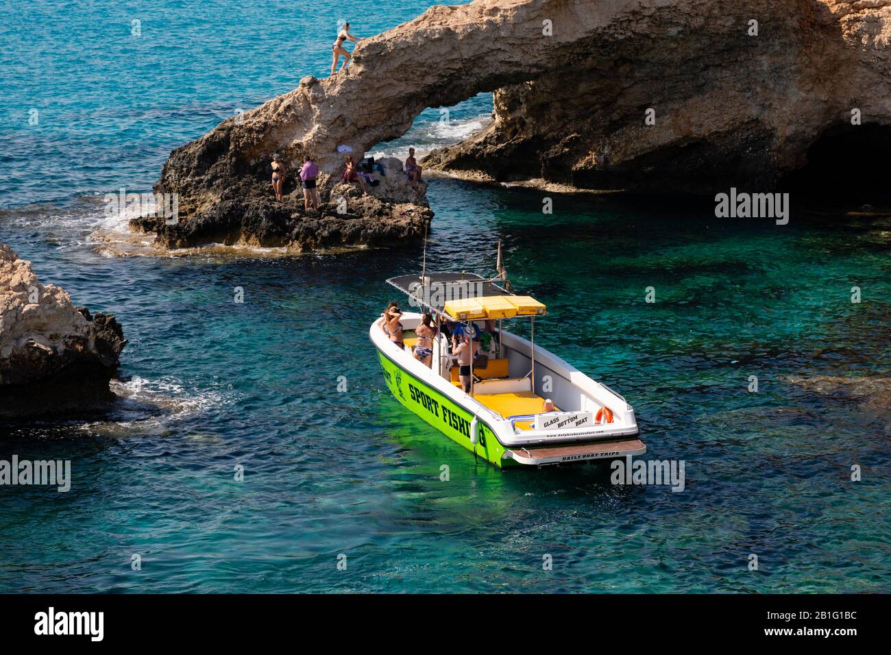 Glasbodenboot mit Touristen an der Liebesbrücke und Meereshöhlen in Ayia Napa, Zypern. Stockfoto