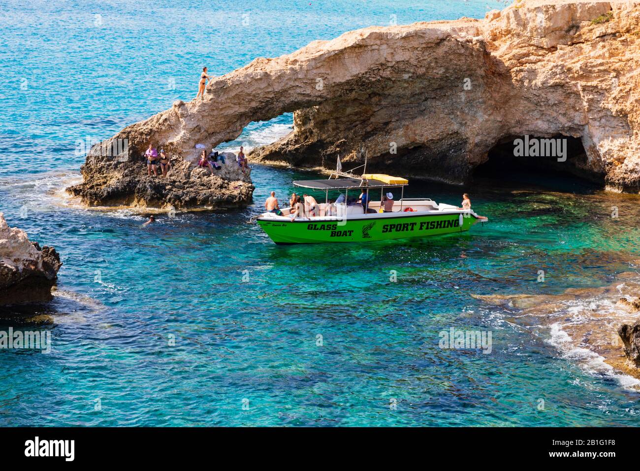 Glasbodenboot mit Touristen an der Liebesbrücke und Meereshöhlen in Ayia Napa, Zypern. Stockfoto