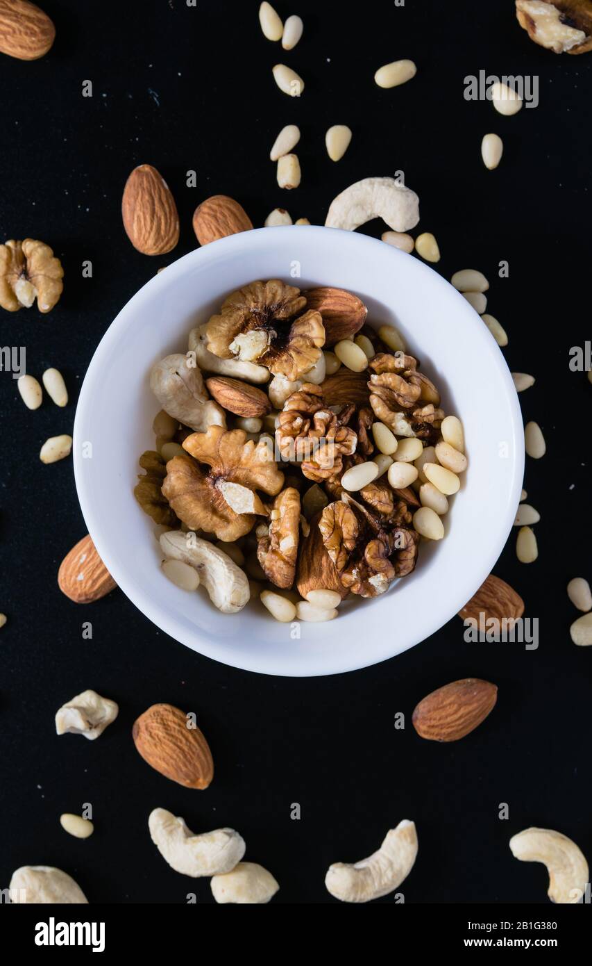 Superfood-Konzept, Mandel, Zeder, Walnüsse, Cashew-Nüsse in einem Teller auf schwarzem Hintergrund Stockfoto