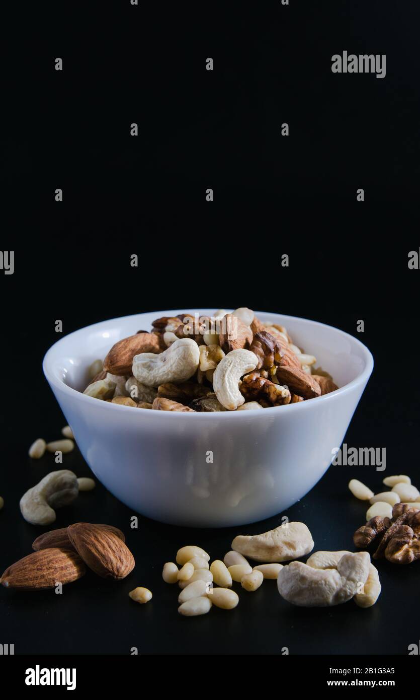 Superfood-Konzept, Mandel, Zeder, Walnüsse, Cashew-Nüsse in einem Teller auf schwarzem Hintergrund Stockfoto