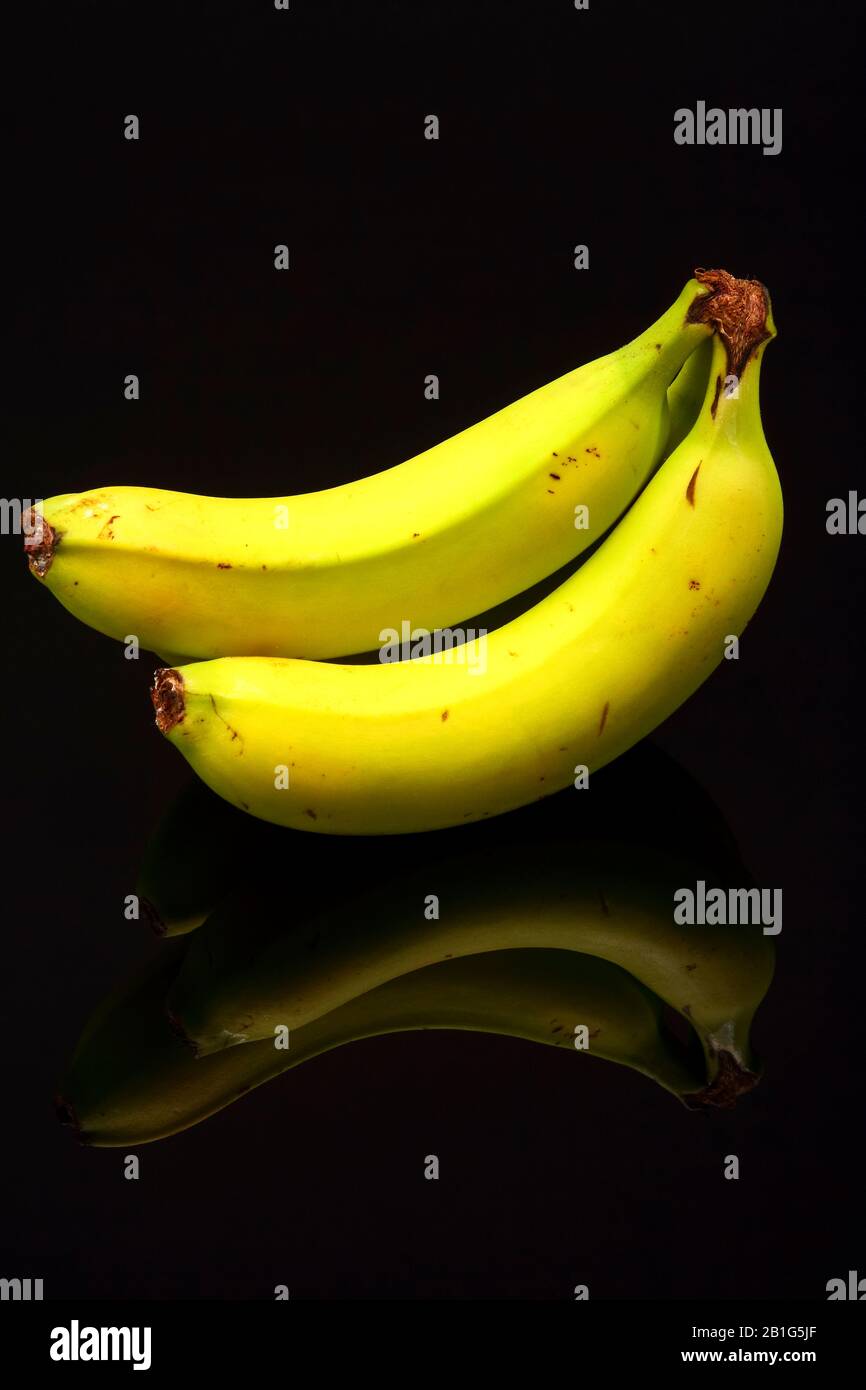 Bananen auf schwarzem Glas mit Spiegelung isoliert Stockfoto