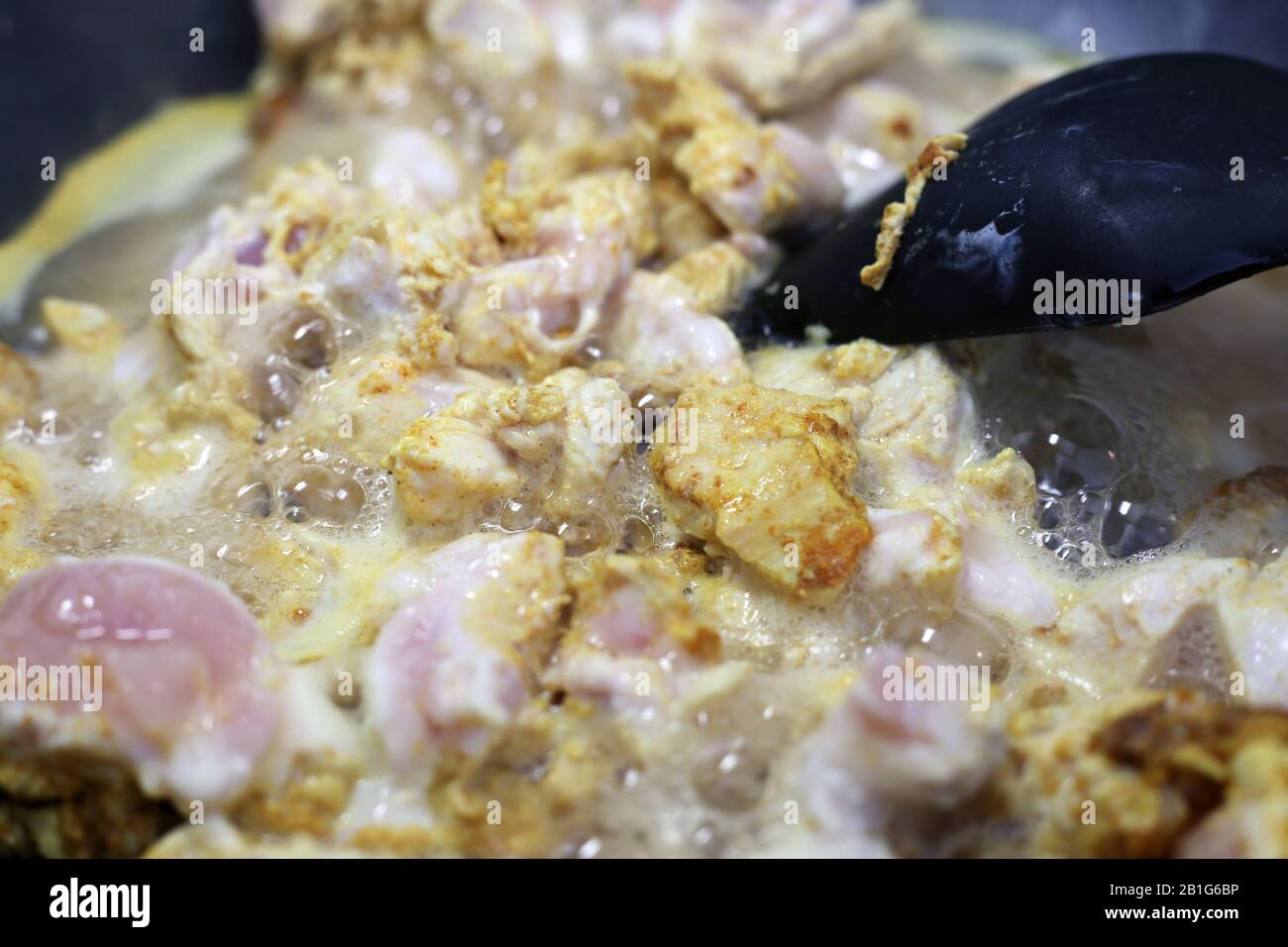 Pfanne braten/kochen einige Hühnerfilets mit bunten Gewürzen wie Curry und getrocknetem Pfeffer. Kochendes, aber gesundes Geflügelfleisch. Stockfoto