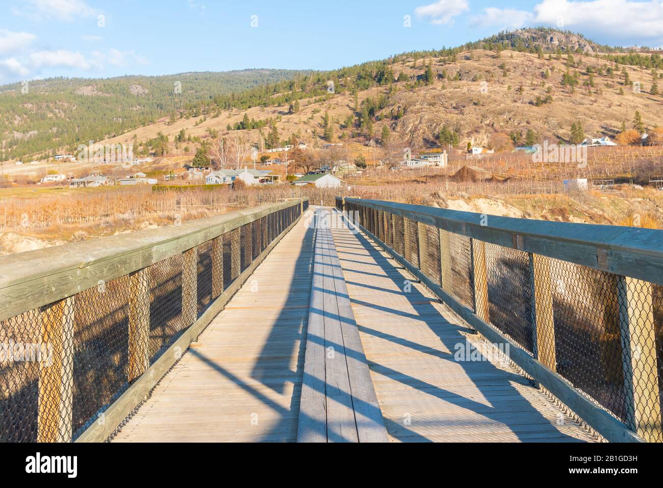 Blick über die Holztrestbrücke auf dem Kettle Valley Rail Trail, um im Herbst Weinberge und Berge zu sehen Stockfoto