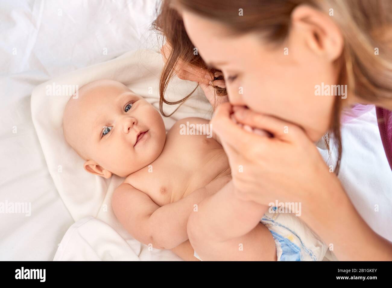 Junge Erwachsene Mutter küsst Füße ihr kleines neugeborenes Baby Stockfoto